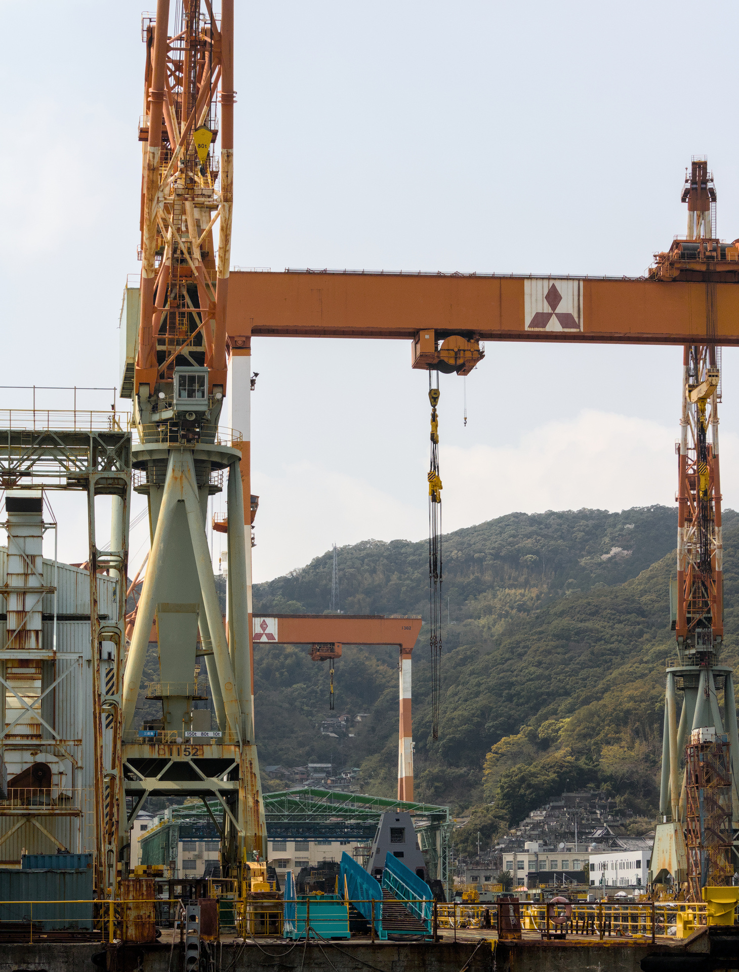 Array of large orange cranes on an industrial dock.